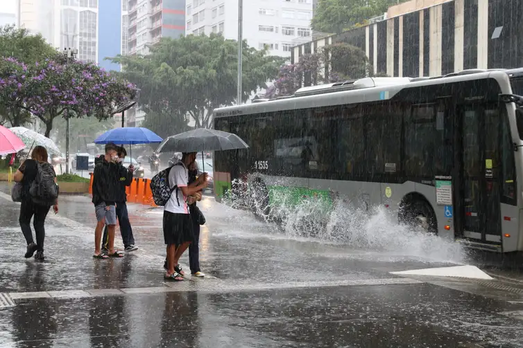 Ônibus joga água na calçada durante chuva na Avenida Paulista.